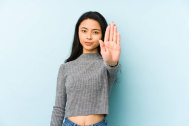 Mavi bir arka planda izole edilmiş genç Çinli kadın elini uzatmış, dur işareti göstererek seni engelliyor..