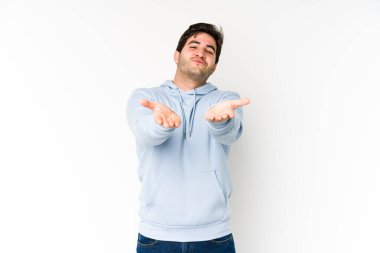 Genç adam beyaz arka planda izole edilmiş dudaklar kıvrılmış ve hava öpücüğü göndermek için avuç içleri tutulmuş..