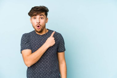 Mavi arka planda izole edilmiş genç bir Arap yan tarafı işaret ediyor.