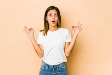 Bej arka planda izole edilmiş genç bir kadın sıkı çalışma gününden sonra rahatlıyor, yoga yapıyor..