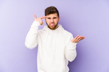 Mor arka planda izole edilmiş genç beyaz adam işaret parmağıyla hayal kırıklığı jesti gösteriyor..