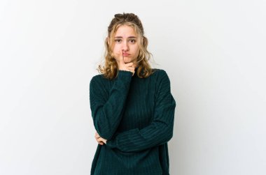 Beyaz arka plandaki genç beyaz kadın kameraya alaycı bir ifadeyle bakmaktan memnun değil..