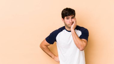 Bej arka planda izole edilmiş, üzgün ve dalgın hisseden, kopyalama alanına bakan genç adam..