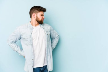 Mavi arka planda izole edilmiş beyaz bir adam sırt ağrısı çekiyor..