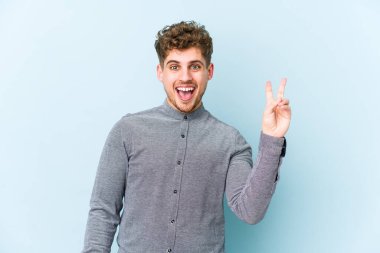 Sarışın, kıvırcık saçlı, beyaz, neşeli ve tasasız bir adam parmaklarıyla barış sembolü gösteriyor..