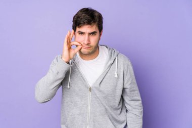 Mor arka planda izole edilmiş genç bir adam parmakları dudaklarında bir sır saklıyor..