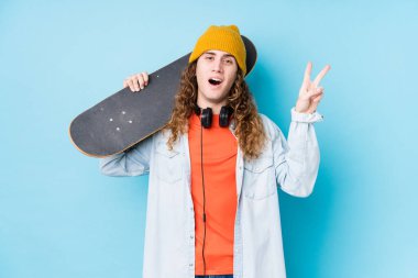 Kafkasyalı genç kaykaycı neşeli ve kaygısız izole edilmiş parmaklarıyla barış sembolü gösteriyor..