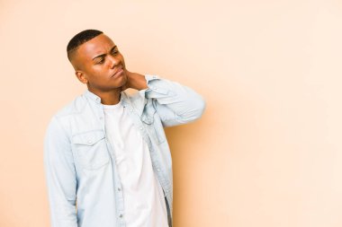 Genç Latin adam bej arka planda izole edilmiş kafasının arkasına dokunuyor, düşünüyor ve bir seçim yapıyor..