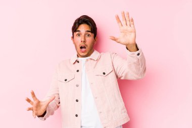 Pembe arka planda poz veren beyaz bir genç yakın bir tehlikeden dolayı izole edilmiş.