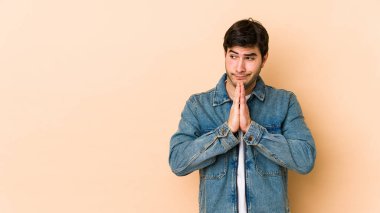 Bej arka planda izole edilmiş genç bir adam dua ediyor, bağlılık gösteriyor, dindar biri ilahi ilham arıyor..