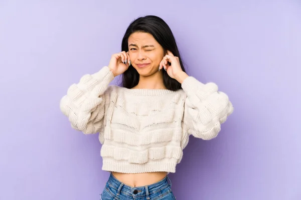 年轻的中国妇女被隔离在紫色的背景下 双手捂住耳朵 — 图库照片