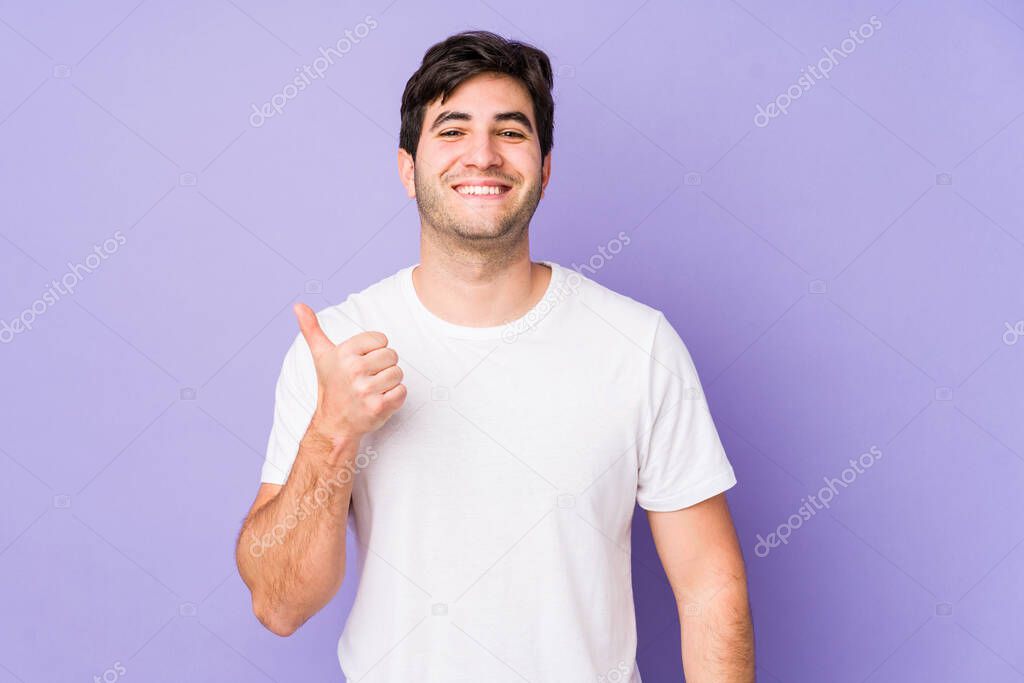 Young man isolated on purple background smiling and raising thumb up