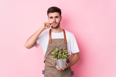 Kafkasyalı genç bahçıvan, parmakları dudaklarında bir sır saklayan bir bitki tutuyor..