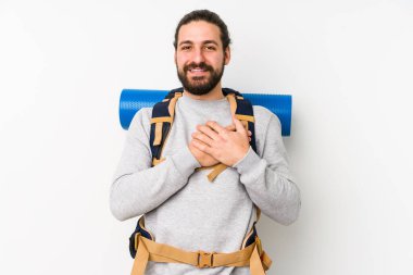 Beyaz bir arka planda izole edilmiş genç bir sırt çantalı adam, avuçlarını göğsüne bastıran dostane bir ifadeye sahiptir. Aşk konsepti.