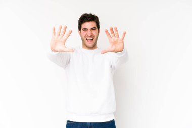 Beyaz arka planda izole edilmiş genç adam on numarayı elleriyle gösteriyor..