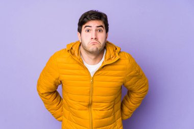 Mor arka planda soyutlanmış genç bir adam omuzlarını silker ve gözleri açık kalır..