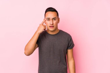 Pembe arka planda poz veren seni gidi Latin adam işaret parmağıyla hayal kırıklığı jesti yapıyor..