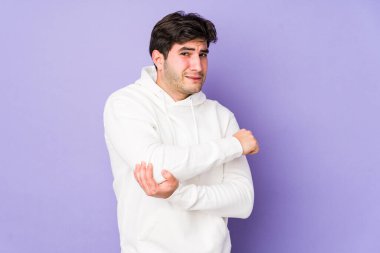 Genç adam mor arka planda izole edilmiş dirsek masajı yapıyor, kötü bir hareketin ardından acı çekiyor..