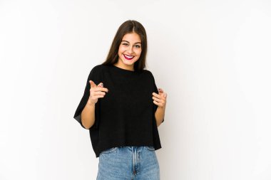 Beyaz arka planda izole edilmiş genç beyaz kadın parmaklarıyla ön tarafı işaret ediyor..