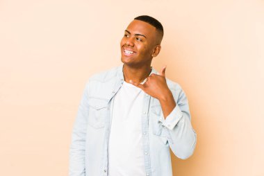 Bej arka planda izole edilmiş genç latin adam parmakları olan bir cep telefonu hareketi gösteriyor..