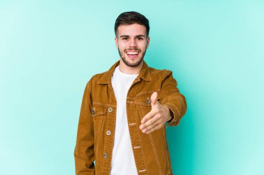 Genç yakışıklı adam kameraya elini uzatıp selam veriyor..