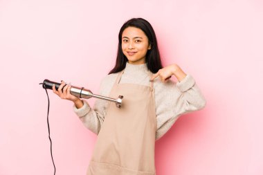 Genç Çinli bir kadın, amaçlarına ve amaçlarına ulaşmayı düşleyen bir mikser tutuyor.