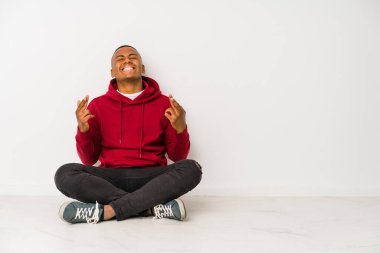 Yerde oturan genç latin adam şans diliyor.