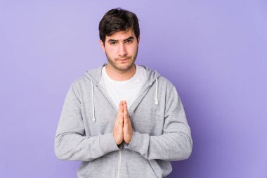 Mor arka planda izole edilmiş genç adam dua ediyor, bağlılık gösteriyor, dindar biri ilahi ilham arıyor..