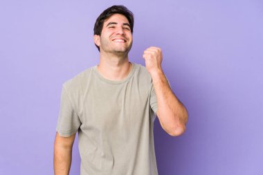 Mor arka planda izole edilmiş genç bir adam zaferi, tutkuyu ve coşkuyu, mutlu ifadeyi kutluyor..