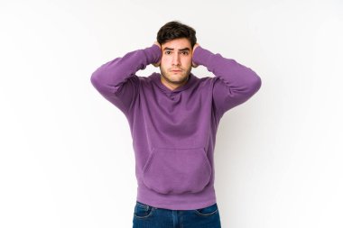 Genç adam beyaz arka planda izole edilmiş. Kulakları elleriyle kapatıyor. Gürültülü sesler duymamaya çalışıyor..