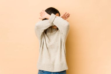 Bej arka planda izole edilmiş genç bir kadın iki kolu çapraz tutuyor, inkar kavramı.