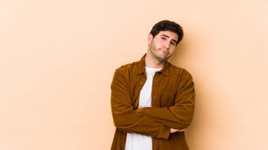 Bej arka planda izole edilmiş, sıkılmış, yorgun ve dinlenmeye ihtiyacı olan genç bir adam..