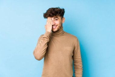 Genç Arap adam izole edilmiş, yüzünün yarısını avuç içiyle kaplayarak eğleniyor..
