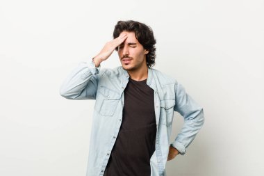 Beyaz bir arka plan karşısında genç yakışıklı bir adam bir şeyi unutuyor. Alnına avuç içi ve gözlerini kapatarak vuruyor..