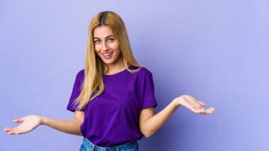 Mor arka planda izole edilmiş genç sarışın kadın hoş bir yüz ifadesi sergiliyor..