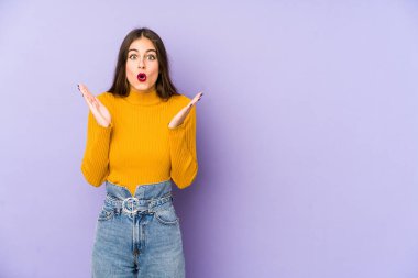 Mor arka planda izole genç beyaz kadın şaşırdı ve şok oldu..