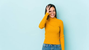 Mavi arka planda izole edilmiş genç bir kadın heyecanlı..