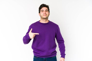 Beyaz arka planda yaşayan genç bir adam gömlek fotokopisini elle gösteriyor, gururlu ve kendinden emin.