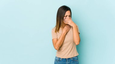 Mavi arka planda izole edilmiş genç bir kadın virüs veya enfeksiyon nedeniyle boğaz ağrısı çekiyor..