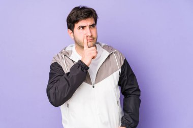 Mor arka planda izole edilmiş genç bir adam ya sır saklıyor ya da sessizlik istiyor..