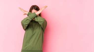 Pembe arka planda izole edilmiş genç beyaz kadın iki kolu çapraz tutuyor, inkar kavramı.