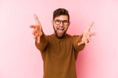 Pembe arka planda izole edilmiş genç beyaz adam kameraya sarıldığı için kendinden emin hissediyor..