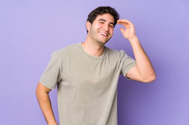 Mor arka planda izole edilmiş genç bir adam neşeli bir şekilde gülüyor. Mutluluk kavramı.