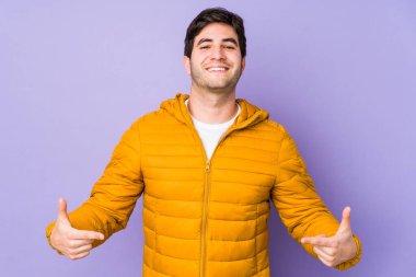 Mor arka planda izole edilmiş genç bir adam parmakları aşağıda, olumlu hisler içinde..