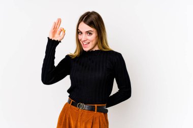 Beyaz arka planda izole edilmiş genç beyaz kadın bir göz kırptı ve elleriyle iyi bir jest yaptı..