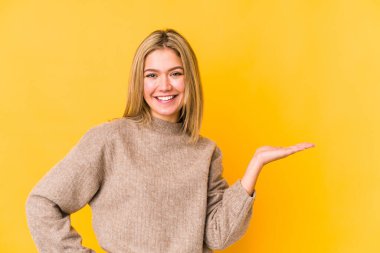 Sarı arka planda izole edilmiş genç sarışın kadın bir avuç içinin fotokopi çektiğini ve belinde başka bir el tuttuğunu gösteriyor..