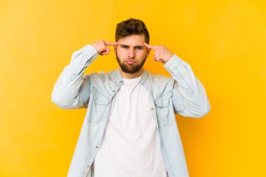 Sarı arka planda izole edilmiş genç beyaz adam bir göreve odaklanmış, işaret parmaklarını işaret ediyor..