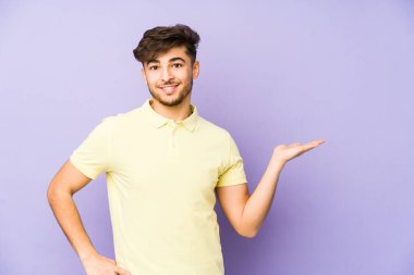 Mor arka planda izole edilmiş genç Arap bir adam bir avuç içinde fotokopi alanı ve belinde bir el daha gösteriyor..