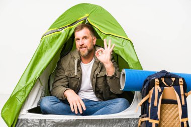 Sunbae, beyaz arka planda izole edilmiş bir çadırda neşeli ve kendinden emin bir şekilde iyi bir jest yapıyor..