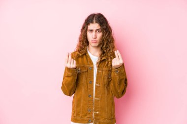 Genç, uzun saçlı adam yalnız poz veriyor. Parası olmadığını gösteriyor..